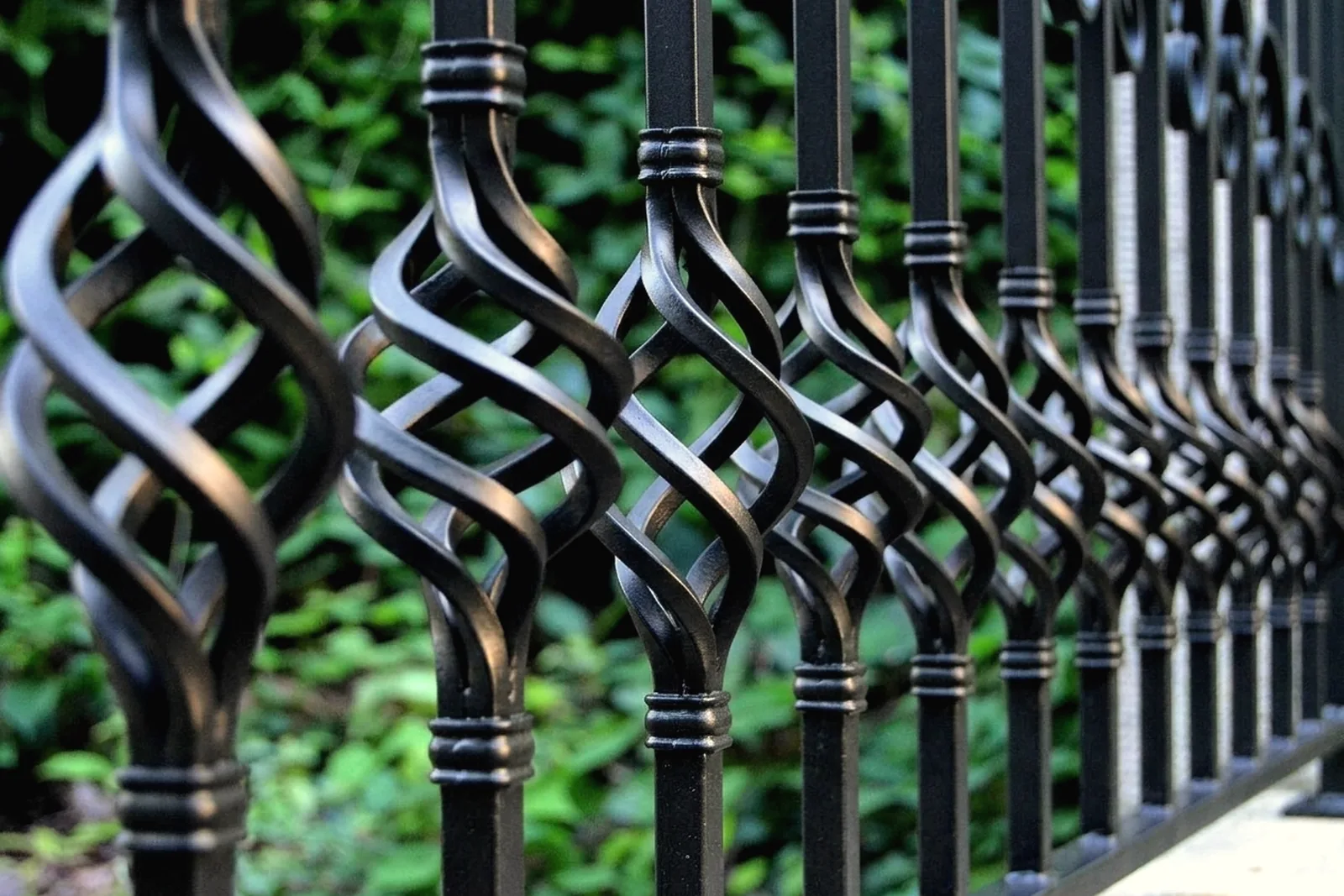 Black wrought iron porch railing with twisted pickets and scrolls